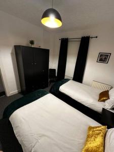 利物浦Anfield end terraced home的一间卧室设有两张床和黑色橱柜