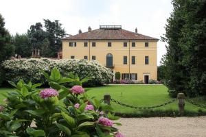 皮内罗洛Agriturismo Il Torrione的一座大房子,带粉红色花的院子