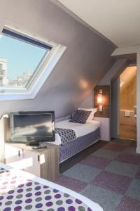 巴黎Hôtel de Charonne的一间卧室配有一张床和一台平面电视