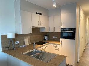 布列登Apartment Residentie Zoë by Interhome的厨房配有白色橱柜和水槽