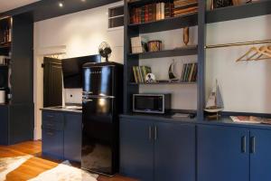 萨凡纳Intimate Library Studio - Minutes to Forsyth Park的厨房配有蓝色橱柜和黑色冰箱。