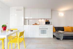 卡斯特尔德费尔斯Castell Beach Aparthotel的厨房配有白色橱柜、桌子和黄色椅子
