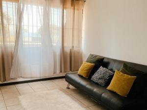蓬塔雷纳斯Frente al mar loft的客厅里设有一张黑色皮沙发,配有窗户