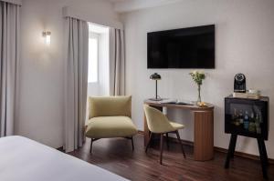 罗马Maison Roma Piazza di Spagna UNA Esperienze的酒店客房配有一张床、一张书桌和一台电视。