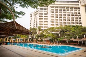 拉各斯Eko Hotel Gardens的酒店游泳池的背景是一座大型建筑
