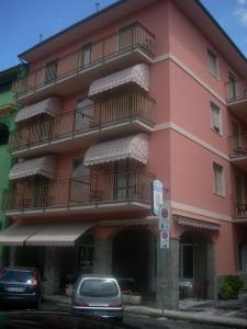 莫内利亚科拉罗酒店的一座粉红色的建筑,设有阳台,门前有车辆停放