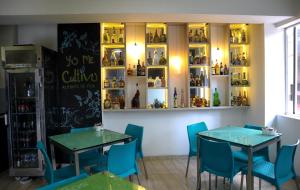 麦德林Hotel Sixtina Plaza Medellin的餐厅设有两张桌子和蓝色椅子,并提供带瓶子的架子