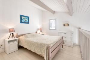 圣马丹德雷Appartement Océanis avec Piscine proche du port的一间白色卧室,配有一张床和两盏灯