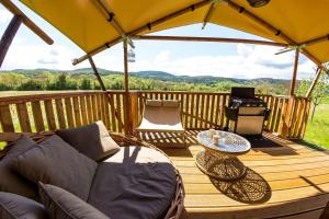 拉戈尔斯Camping et Lodges de Coucouzac的木制甲板配有沙发和遮阳伞