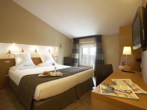 阿西西波尔塔努欧瓦酒店的酒店客房设有一张大床和一张桌子。