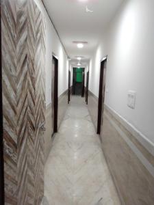 阿格拉OYO S S Palace的一条带白色墙壁的走廊和一条带木门的长走廊
