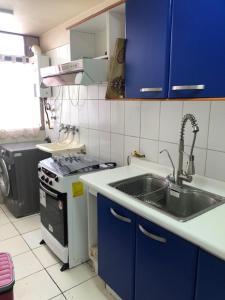伊基克departamento Iquique的厨房配有水槽、炉灶和蓝色橱柜。
