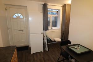 达特福德Large Comfy Studio Flat, Next to Dartford Town Centre, Separate Kitchen, Wifi的客房设有冰箱、桌子和窗户。