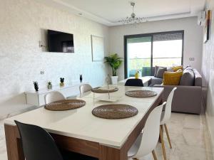 穆罕默迪耶luxe appartement met zeezicht en zwembad Mohammedia Parc的用餐室以及带桌椅的起居室。