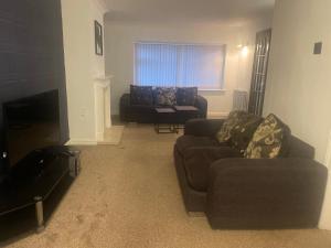 伯明翰4 Bed Comfy House in Birmingham的客厅配有2张沙发和1台平面电视