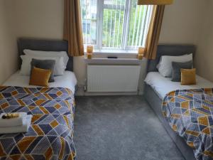 威勒尔5Bed House Wirral near Liverpool Chester的客房设有两张床和窗户。