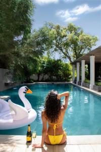 TokaiSteenberg Hotel & Spa的坐在游泳池旁的女人,有天鹅