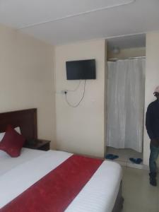 ThikaRAYA hotel Nairobi的卧室配有一张床,墙上配有电视。