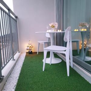 仁川市Lovely House的绿色地毯上配有白色桌椅的阳台
