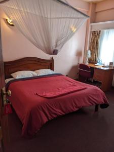 内罗毕Metro Hotel的一间卧室配有红色的床和红色毯子