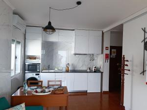 蓬塔德尔加达瓦拉多斯公寓的厨房配有白色橱柜和木桌