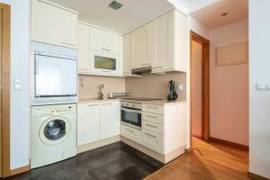 巴约讷One bedroom appartement with wifi at Baiona的厨房配有白色橱柜、洗衣机和烘干机