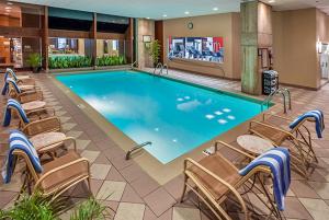 费城费城机场希尔顿逸林酒店的酒店客房的大型游泳池配有椅子