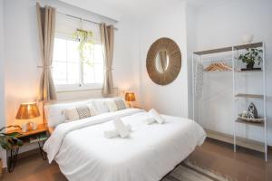 内尔哈Naim Guest House Nerja的白色的卧室设有一张白色大床和一个窗户。
