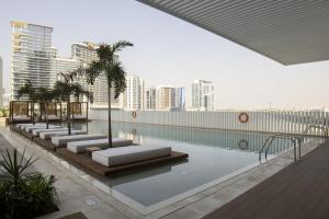 迪拜Business Travel Ready Studio at Upside Living的一座城市里带躺椅和棕榈树的游泳池