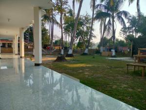 JaliapāraSurjasto Resort的庭院里种有棕榈树和水