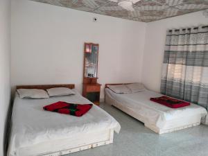 JaliapāraSurjasto Resort的一间卧室配有两张带红色枕头的床。