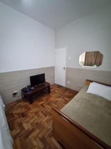 贝洛奥里藏特Comodidade e Segurança no Centro的一间卧室配有一张床和一张桌子及一台电视
