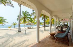 珀拉什奇亚Ocean Crush- Beachfront & Resort Amenities的海滩上的房子,配有椅子和棕榈树