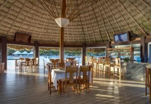 珀拉什奇亚Ocean Crush- Beachfront & Resort Amenities的一间设有桌椅和屋顶的餐厅