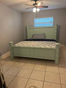 克利尔沃特5 Mins from Clearwater Beach with Free Wi-Fi & TV的一间卧室配有一张绿色的床和吊扇