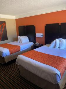 查尔斯湖查尔斯湖豪生国际酒店的橙色墙壁的酒店客房内的两张床