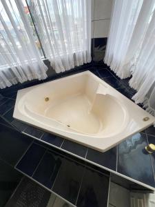 锡诺普Suíte de Luxo no centro, com hidromassagem e closet的浴室设有白色浴缸,配有窗帘