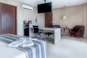 帕尔马斯Hplus Premium Palmas的酒店客房,配有一张床、一张桌子和椅子