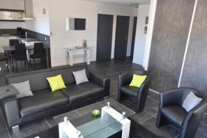 滨海阿热莱斯Appartement de 2 chambres avec piscine partagee terrasse et wifi a Argeles sur Mer a 3 km de la plage的客厅配有黑色沙发和两把椅子