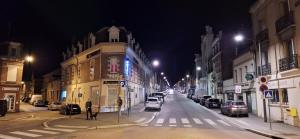 圣康坦Hôtel Le Saint Quentin的夜间有车辆停放的城市街道