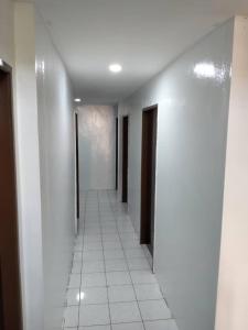 拿笃Hotel Iramanis的走廊设有白色墙壁和白色瓷砖地板