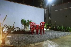 瓜鲁雅Casa com piscina, enseada Guarujá sp.的天井上两把红色椅子围着桌子