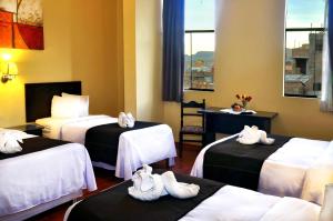 普诺Casona Plaza Hotel Centro的酒店客房,配有三张床和毛巾