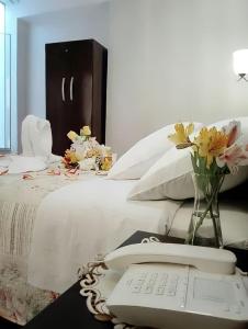 塔克纳HOTEL CASA REAL的一张带电话和花瓶的白色床