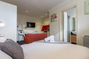 墨尔本Studio Apartment in the heart of Fitzroy的卧室配有白色的床和红色椅子