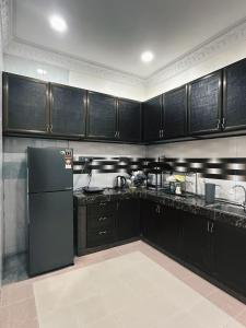 居銮Yolo Homestay的厨房配有黑色橱柜和黑色冰箱。