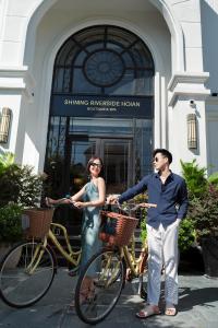 会安Shining Riverside Hoi An Boutique & Spa的站在自行车旁的男人和女人