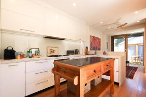 悉尼Charming 3-Bedroom Terrace in the Heart of Glebe的一间厨房,配有白色的橱柜和木制岛屿