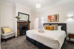 奥兰治Sanlor Suite 2 - Luxury, Comfort & Style的一间卧室配有一张带壁炉和椅子的床。