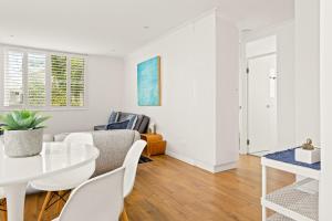 悉尼Chic apartment footsteps from Manly Beach的白色的客厅配有白色的桌子和椅子